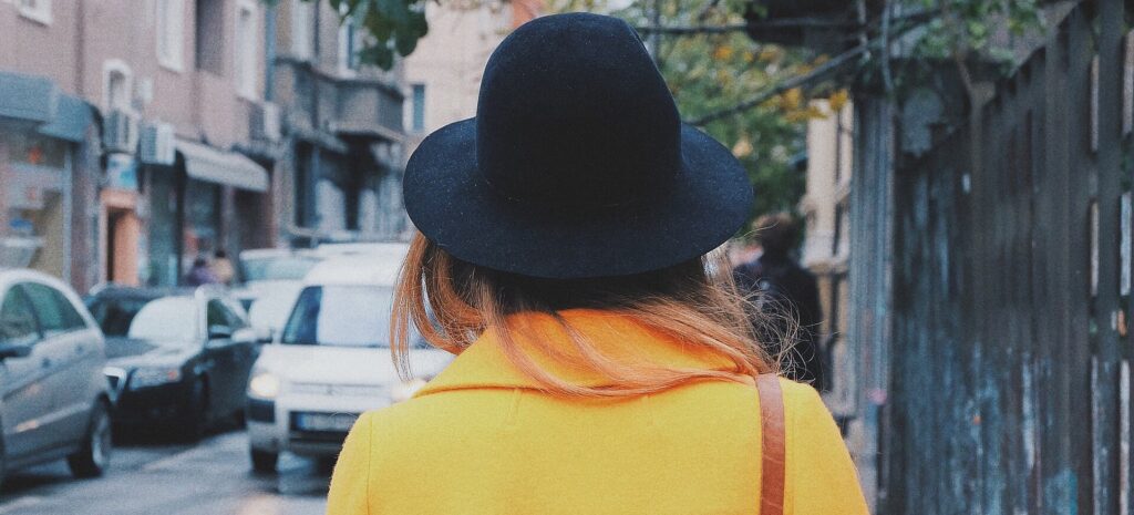 黄色のコートを着て街を歩く女性